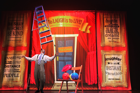 man on stage balancing a ladder on his chin